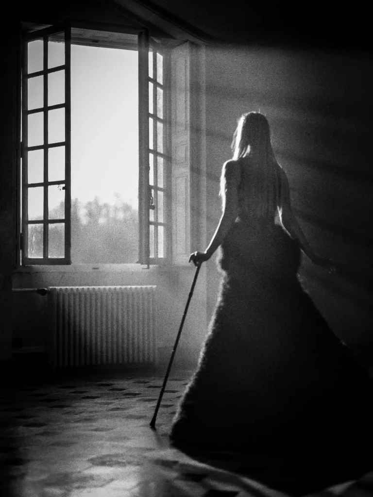 Scène éditoriale, femme dans une pièce sombre, éclairée par un faisceau lumineux éblouissant.