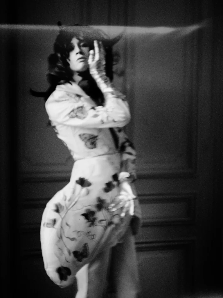 Portrait éditorial, personne en tenue féminine, mise en scène artistique en noir et blanc.