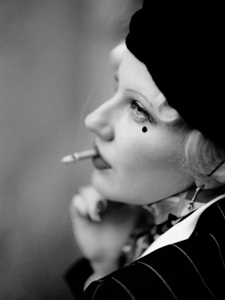 Portrait artistique, femme au style vintage, geste élégant, cadrage rapproché.