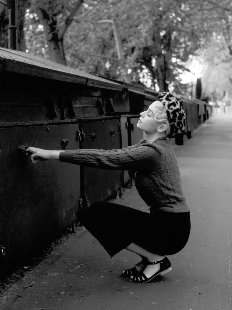 Photographie rétro en noir et blanc, femme sur les quais de scène de Paris, ambiance élégante.
