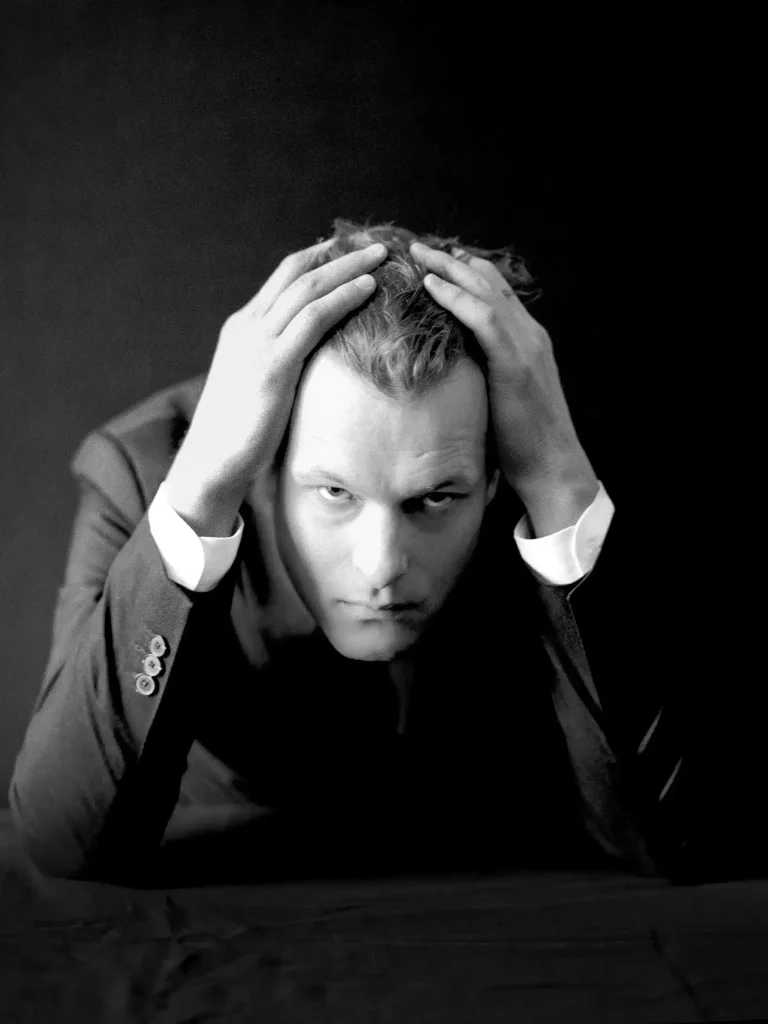 Portrait éditorial, homme habillé en smoking, geste dramatique, visage entre les mains.