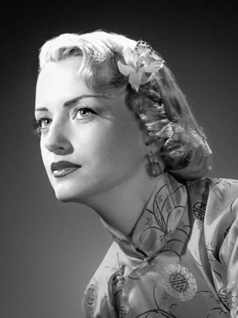 Femme au look années 50, posture contemplative, photographie en noir et blanc.