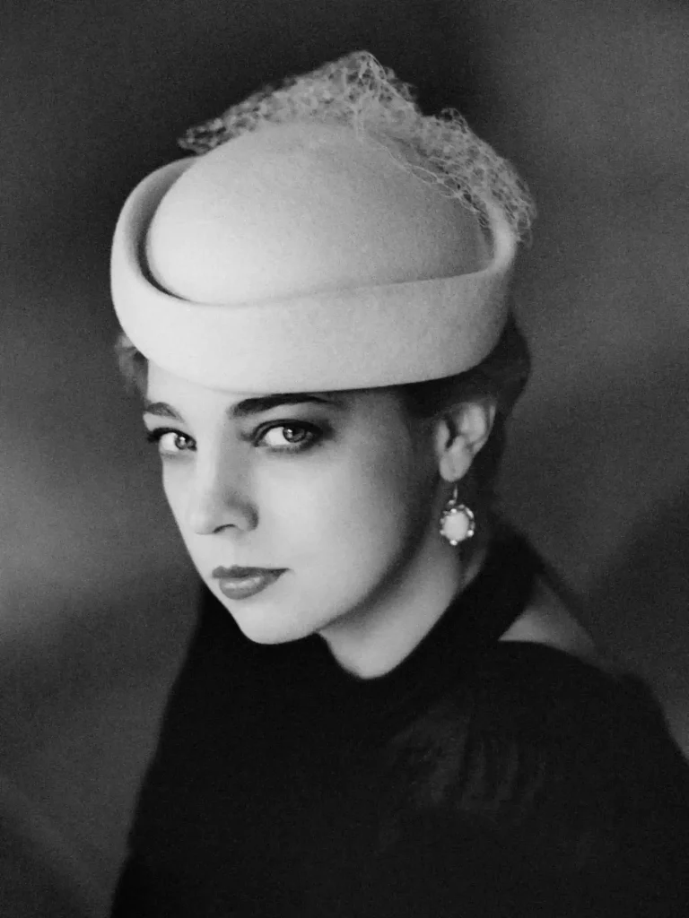 Femme au look années 50, posture contemplative, photographie en noir et blanc.